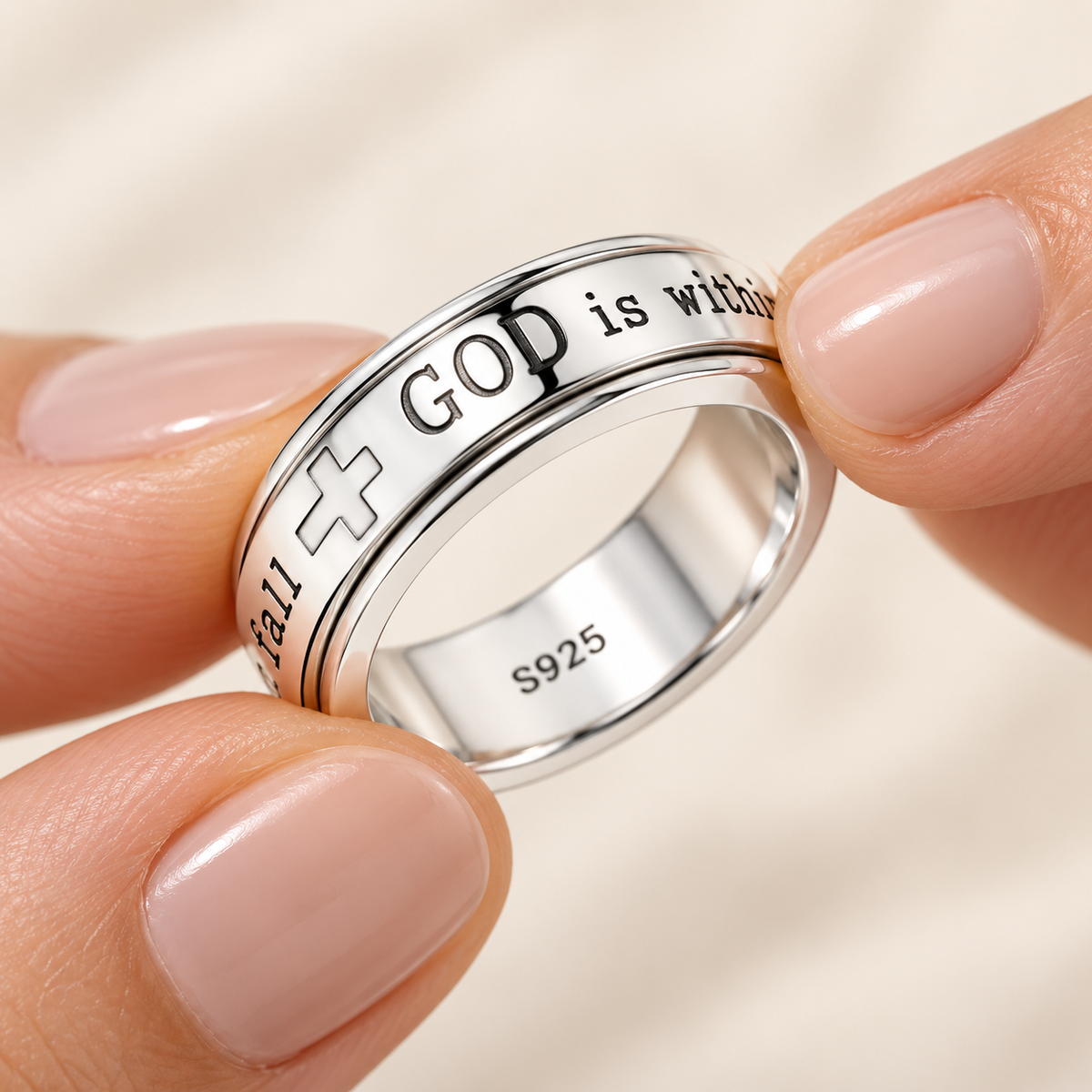 Fingers gently turning the outer band of the silver Psalm 46:5 ring