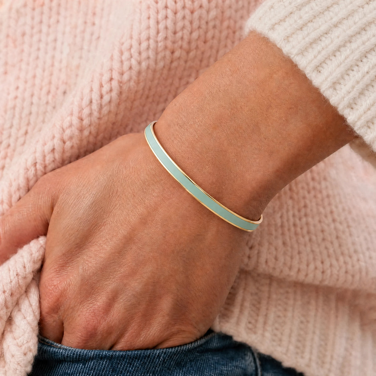 Green enamel reminder cuff worn as one continuous band with soft knitwear