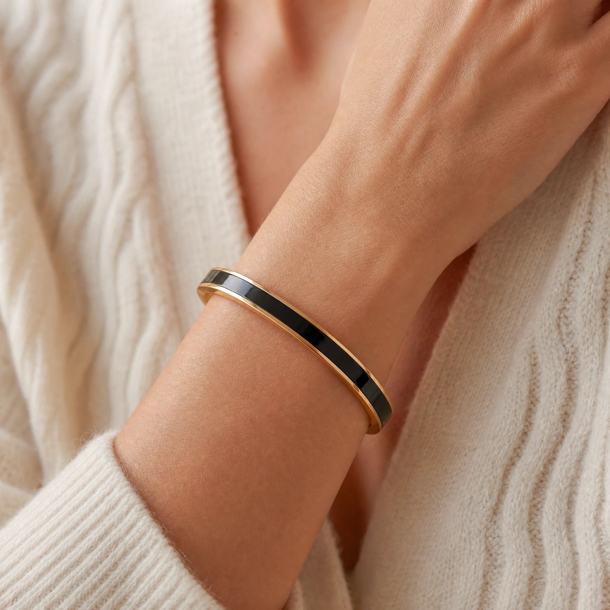 Black enamel reminder cuff worn as one continuous band with soft ivory knitwear