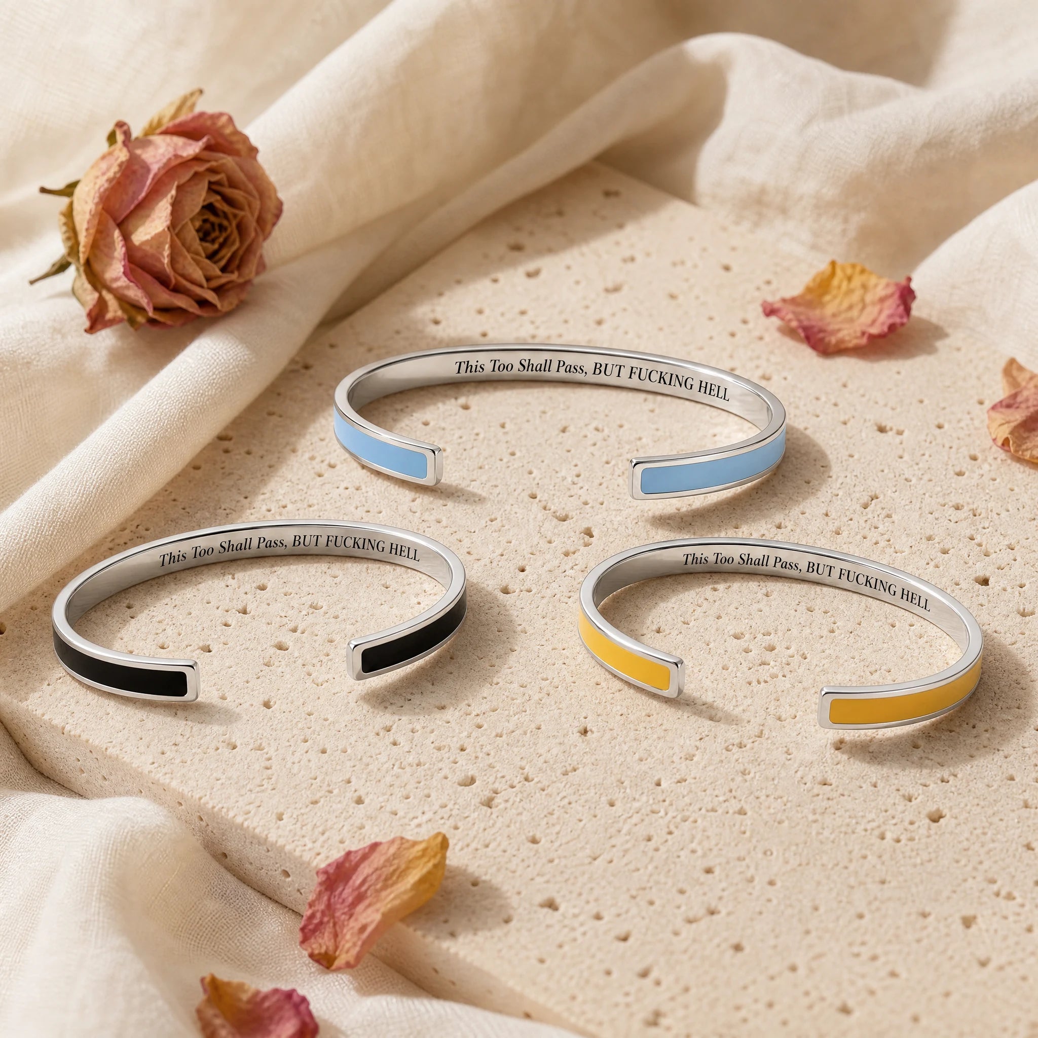Three silver enamel reminder cuffs in blue black and yellow showing the engraved quote