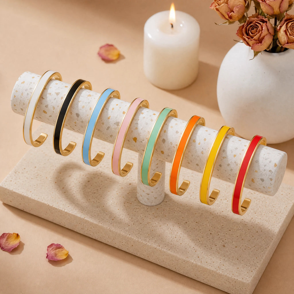 Eight gold enamel reminder cuffs in all available colors displayed on terrazzo