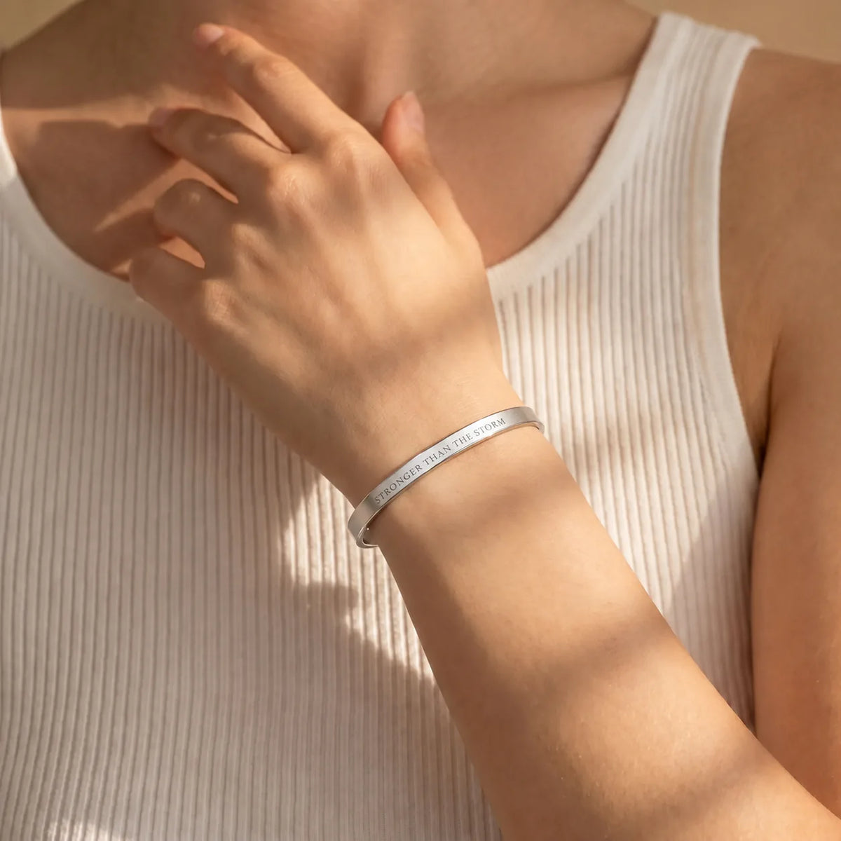Silver Stronger Than The Storm engraved cuff bracelet worn in warm sunlight
