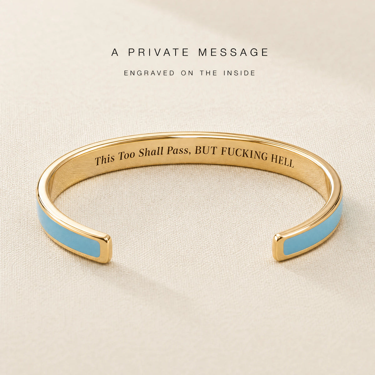 Blue enamel cuff opened to show This Too Shall Pass engraved inside