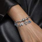 CALEO Heart & Geometric Clasp Snake Chain Bracelet lifestyle on black silk with Compass, Moon, Angel, and Celtic charms