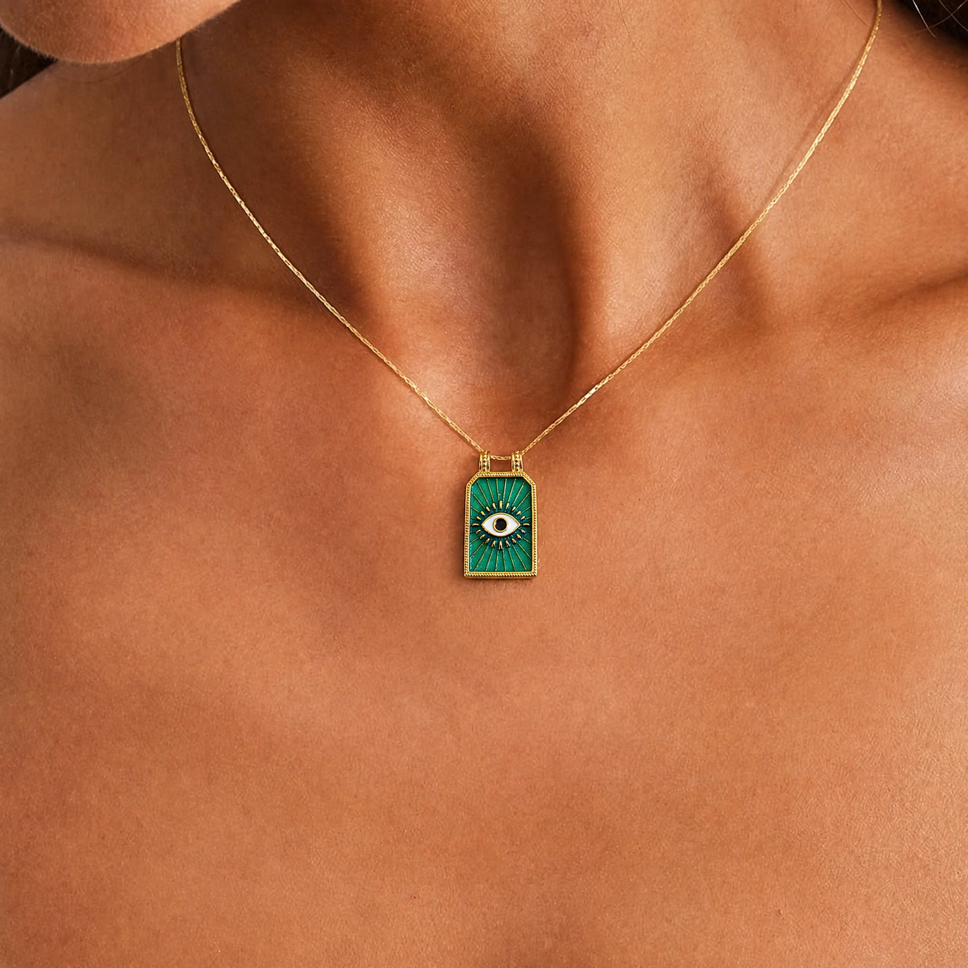 Gold teal evil eye talisman necklace worn as a modern symbol of protection