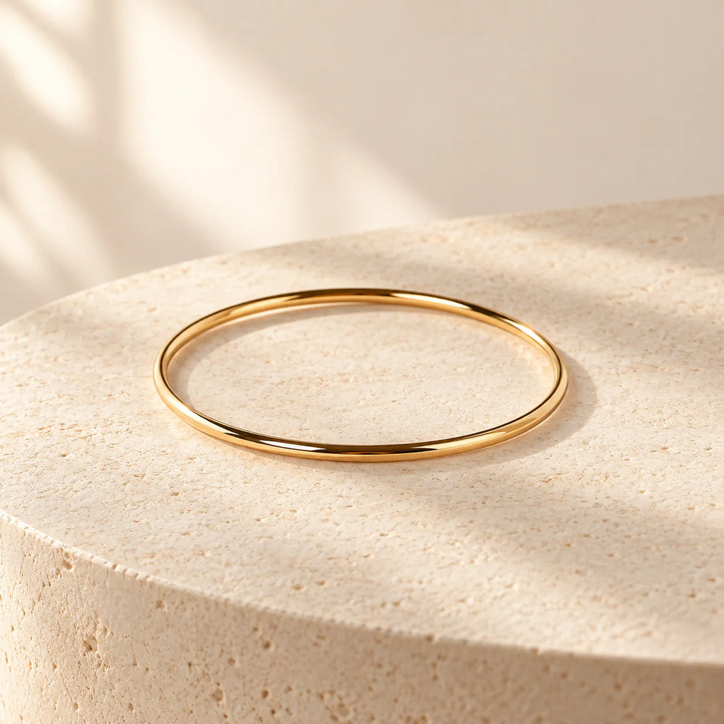 Gold Aurelia Essential Bangle on a warm ivory background