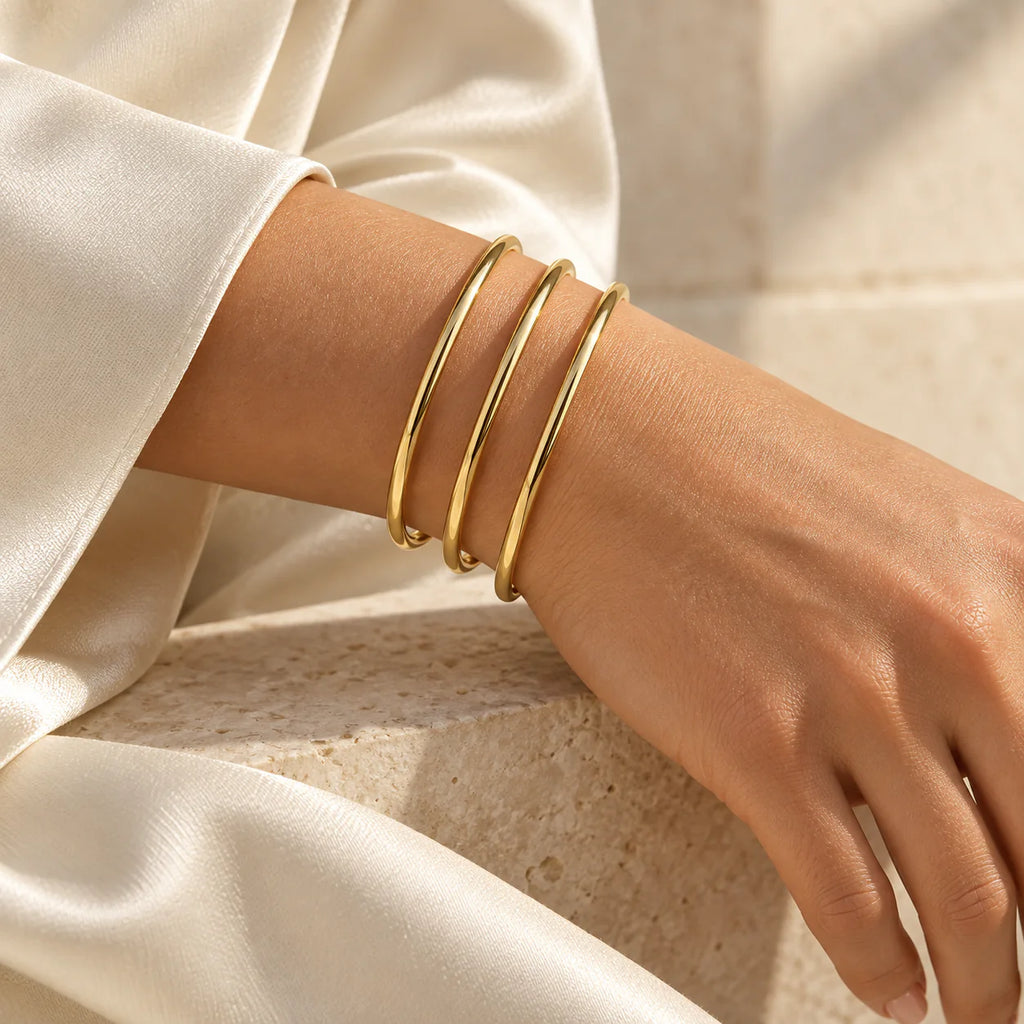 Three Aurelia Essential Bangles stacked in Gold, Rose Gold and Silver