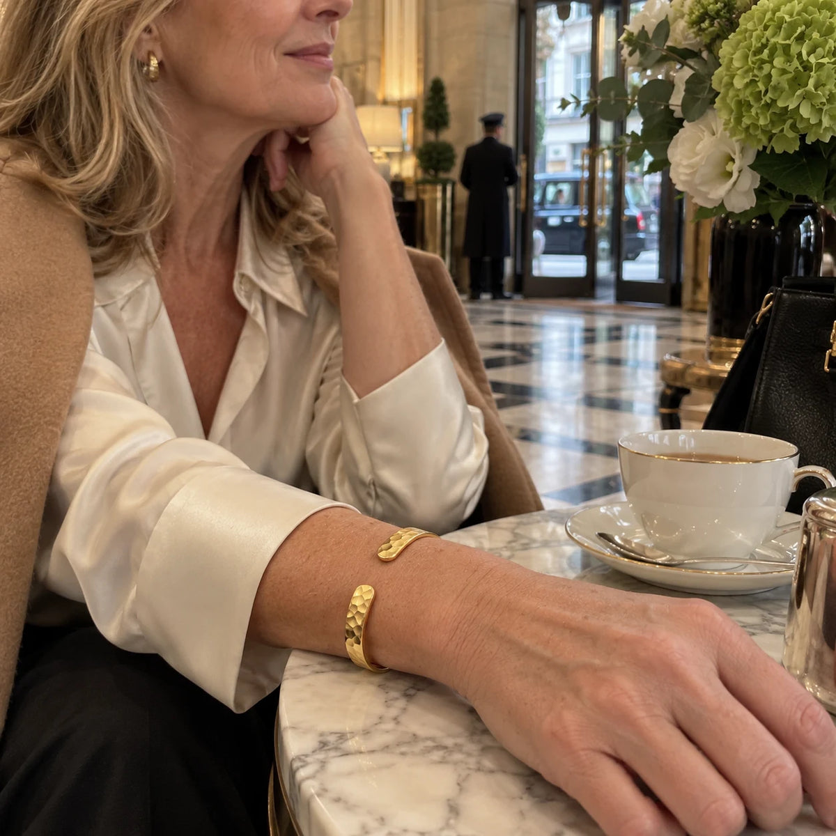 Gold hammered cuff worn by a mature British woman outside a Mayfair hotel