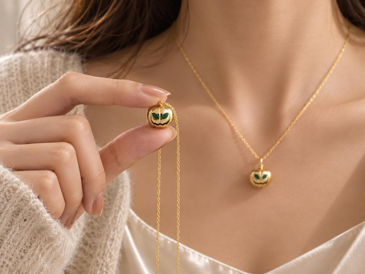 Model wearing and holding emerald birthstone pumpkin necklaces