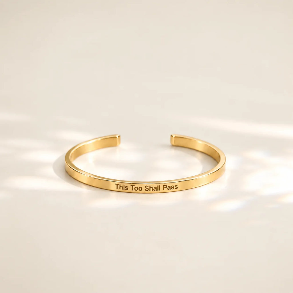 Gold This Too Shall Pass Slim Cuff with outside engraving in soft sunlight