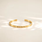 Gold This Too Shall Pass Slim Cuff with outside engraving in soft sunlight