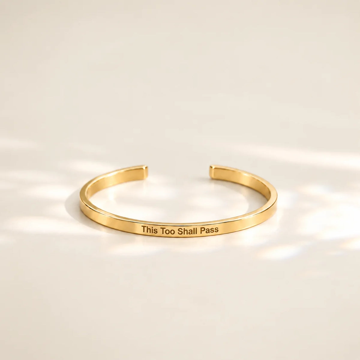 Gold This Too Shall Pass Slim Cuff with outside engraving in soft sunlight