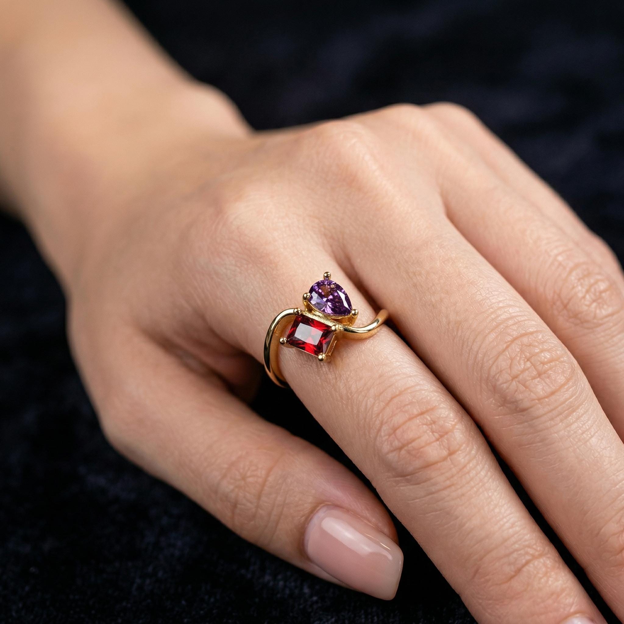 18K gold plated two stone birthstone ring with red and purple stones worn on hand