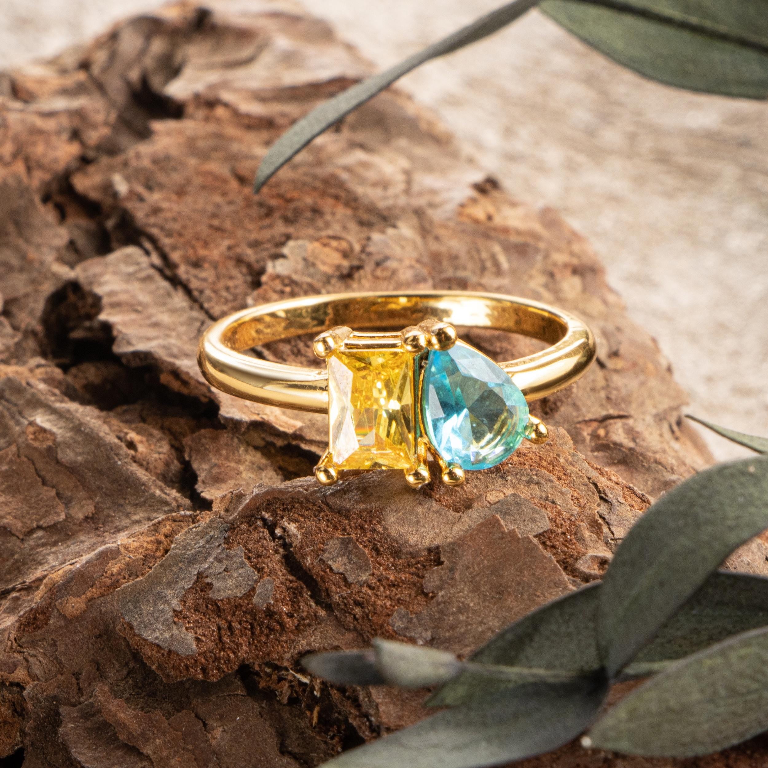 18K gold plated two stone birthstone ring with yellow and aquamarine stones on natural wood